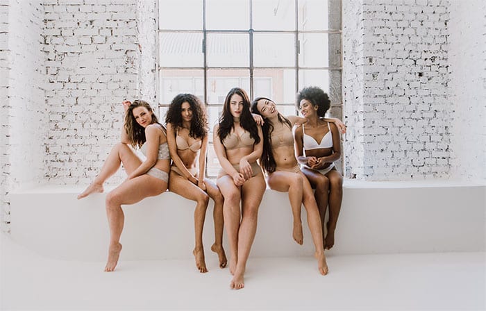 Five beautiful women sitting together smiling and showing their results from Always Beautiful. 