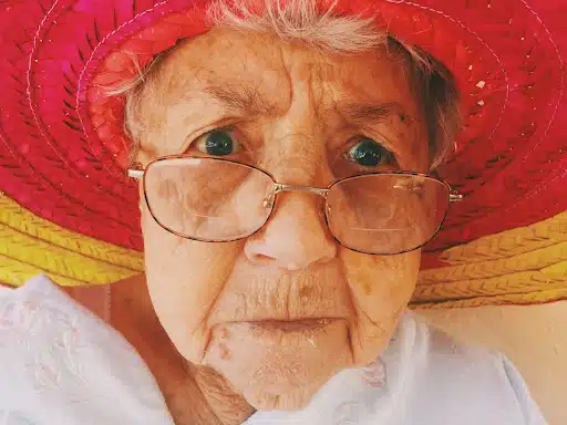 an image of an old woman wearing eyeglass with a red hat