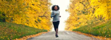 a woman jogging with a background of autumn trees