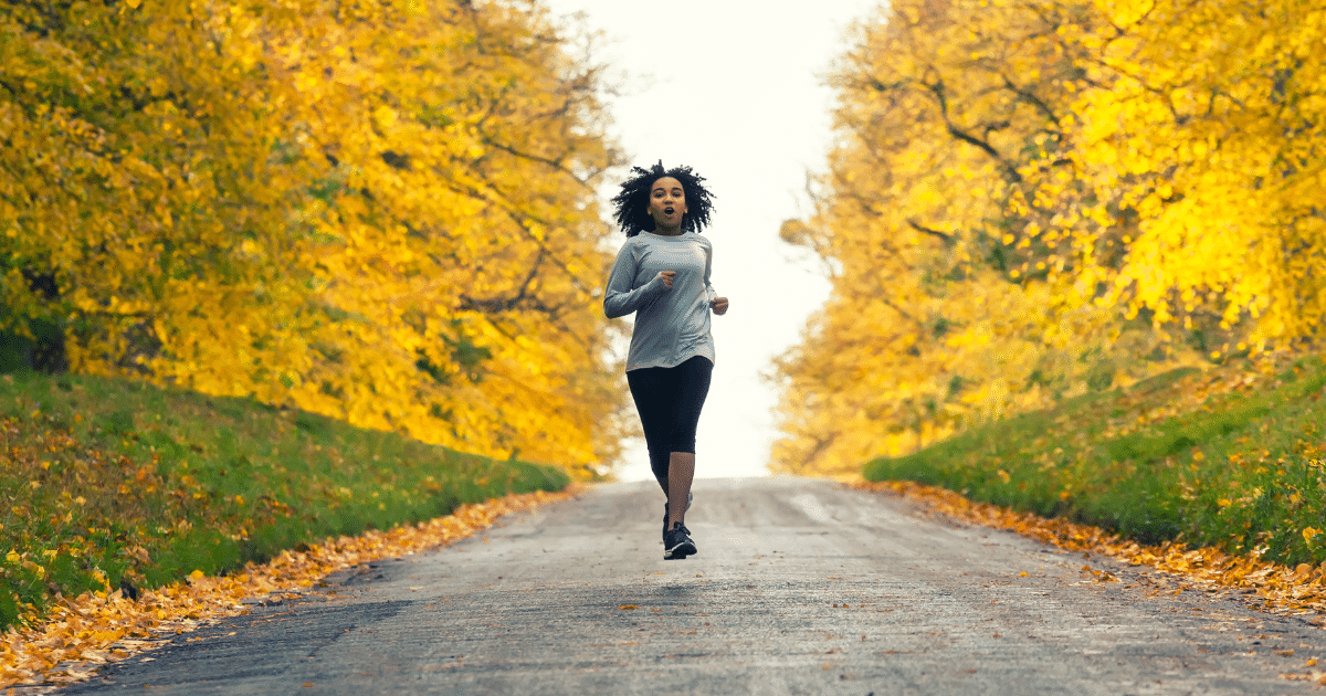 a woman jogging with a background of autumn trees